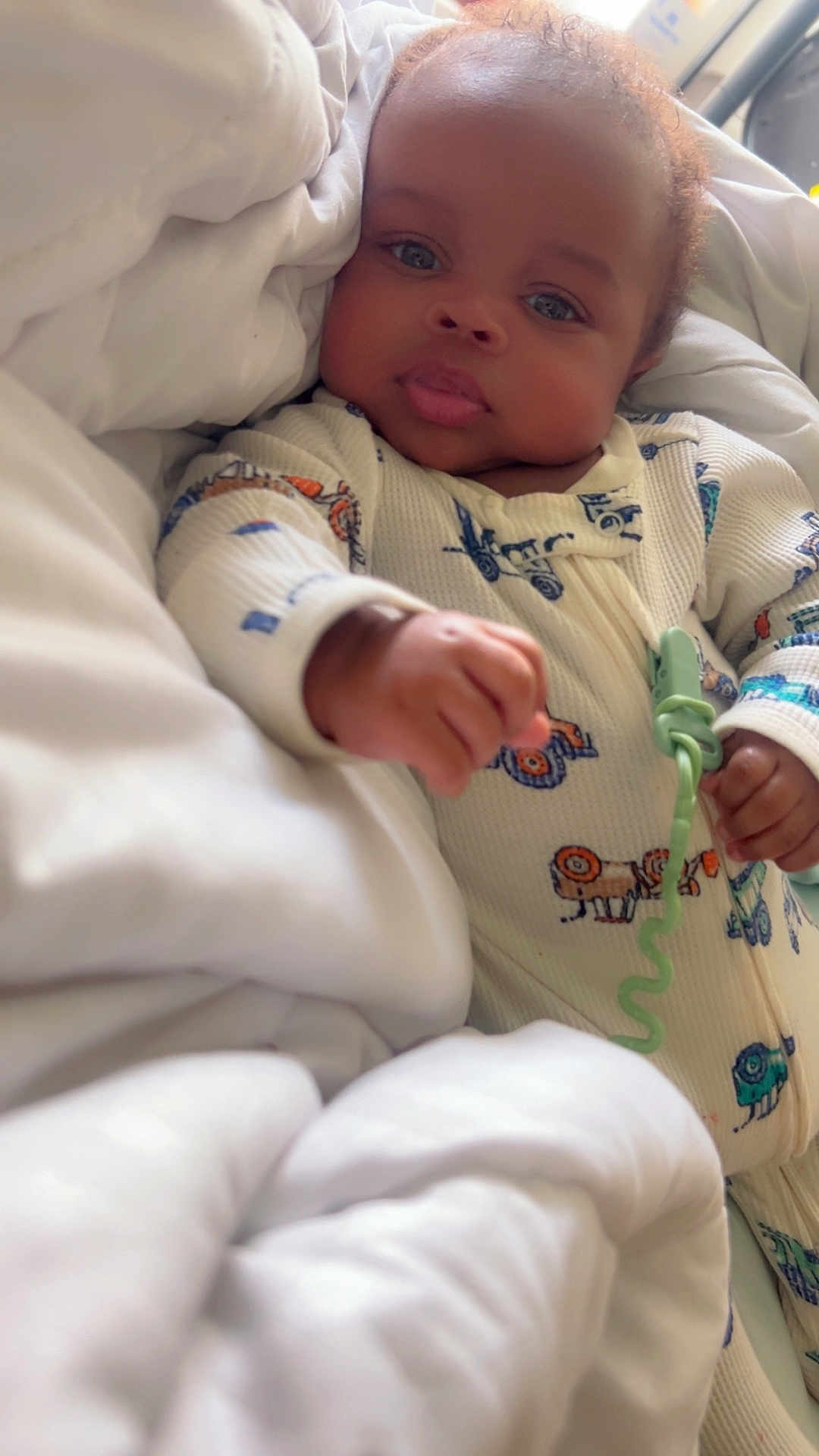 Marlon Shaw Jr is registered to the contest to win money with this photo: baby, infant, blanket, onesie, hand, face, cozy, cute, indoors, bed, sleepwear, child, peaceful, soft, portrait, person, lying_down, young, warm, comfort