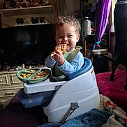 Lucius joined the competition — help win amazing prizes! baby_seat, blanket, cabinet, child, curly_hair, dog, dolls, food, happy, home_interior, indoor, person, pink_cushion, plate, purple_curtain, shelf, smiling, snack, television, toddler