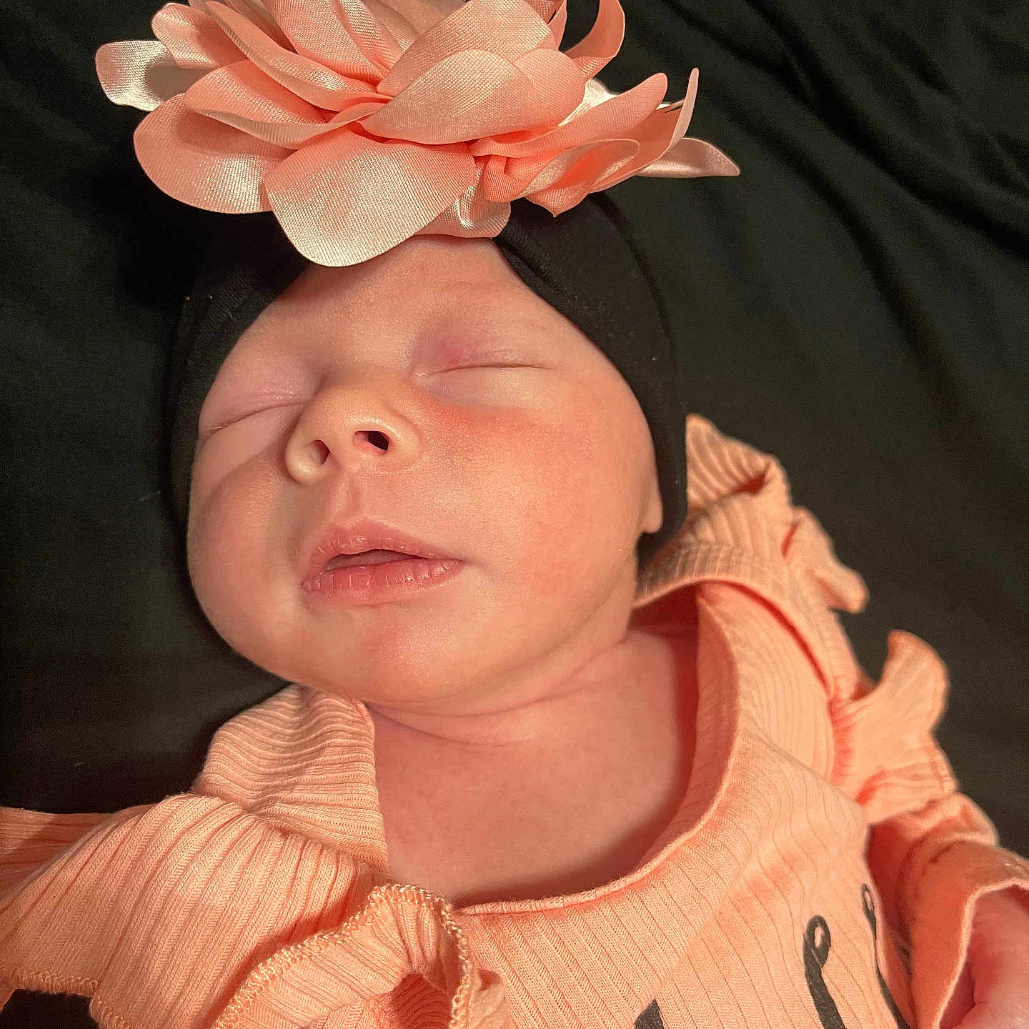 Hadley is registered to the contest to win money with this photo: baby, black_background, child, closeup, delicate, face, flower, headband, infant, newborn, outfit, peaceful, peach, portrait, resting, ruffles, skin, sleeping, soft, young