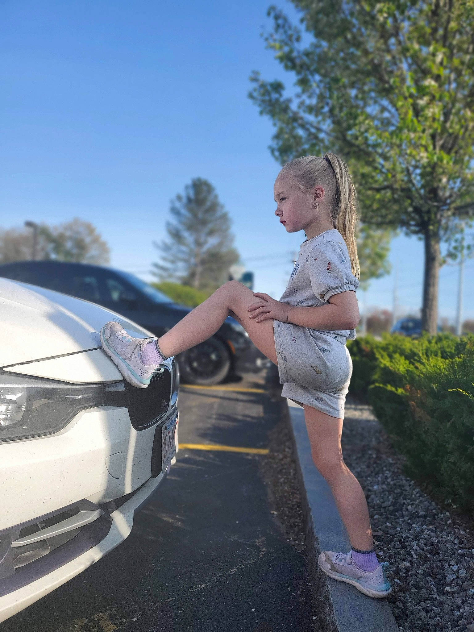 Annmarie joined the competition — help win amazing prizes! asphalt, automotive_design, automotive_exterior, automotive_lighting, automotive_tire, bumper, car, grille, headlamp, hood, motor_vehicle, person, personal_luxury_car, plant, rim, rolling, shorts, sky, tree, vehicle