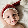 baby, bare_chest, blanket, cheek, cozy, cute, eyes, face, happy, holiday_hat, indoors, infant, knit_hat, lying_down, newborn, pompom, portrait, smiling, soft_texture, tongue_out