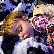 Bailey is registered to the contest to win money with this photo: child, sleeping, toddler, portrait, face, blonde_hair, pajamas, blanket, plush_toy, stuffed_animal, bedtime, cozy, indoors, resting, lying_down, closed_eyes, soft_lighting, colorful_clothing, sports_pattern, comforter