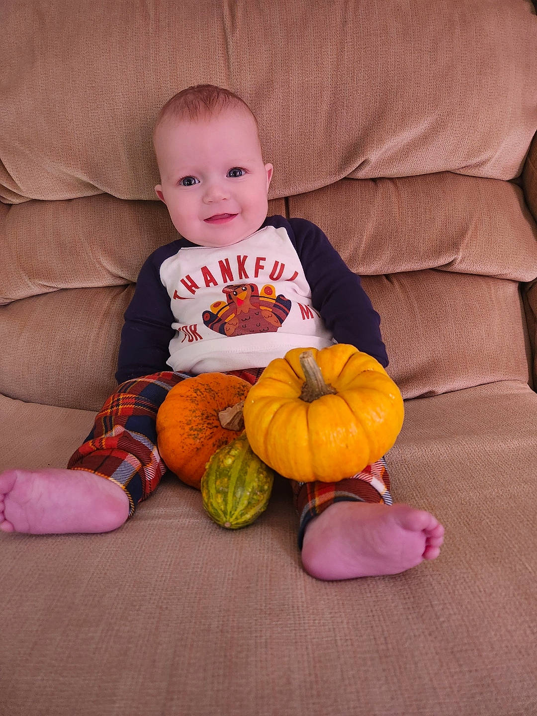 Emilia is registered to the contest to win money with this photo: arm, baby_toddler_clothing, calabaza, cheek, comfort, couch, dress, eye, finger, floor, flooring, head, human_body, iris, joy, leg, orange, person, pumpkin, smile