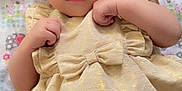 Lilyanah Andre is registered to the contest to win money with this photo: baby, infant, child, dress, golden_dress, bow, blanket, patterned_blanket, lying_down, cute, curious_eyes, small_hands, soft_skin, indoors, portrait, close_up, adorable, toddler, hair_tuft, expression