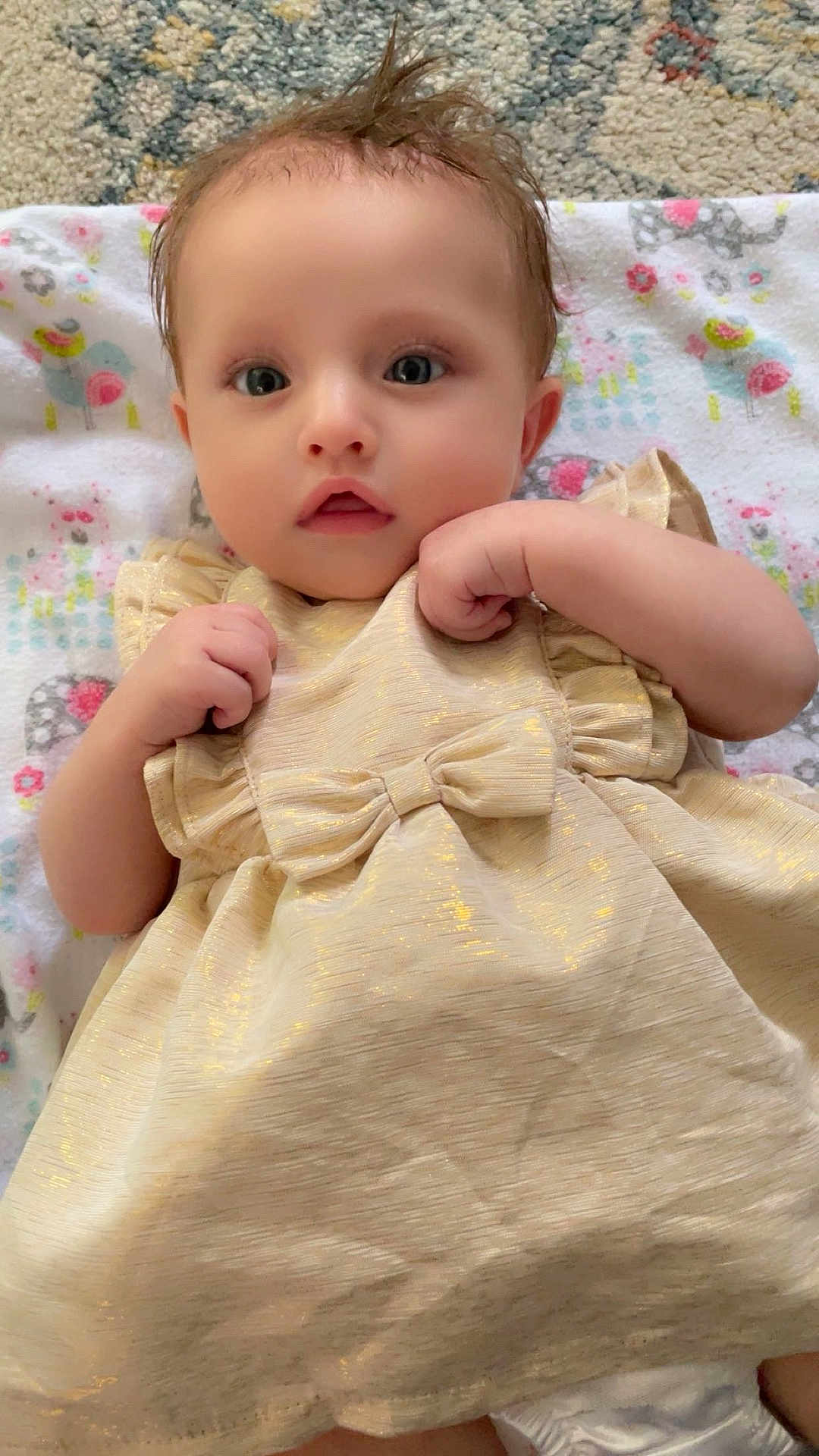 Lilyanah Andre is registered to the contest to win money with this photo: baby, infant, child, dress, golden_dress, bow, blanket, patterned_blanket, lying_down, cute, curious_eyes, small_hands, soft_skin, indoors, portrait, close_up, adorable, toddler, hair_tuft, expression