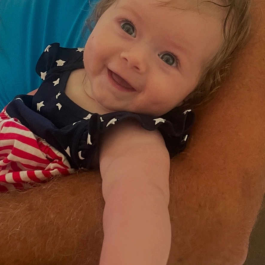 Sophia joined the competition — help win amazing prizes! arm, baby, blue_shirt, child, closeup, couch, cute, expression, face, hair, happy, holding, human, indoor, infant, person, pony_tail, portrait, skin, smile