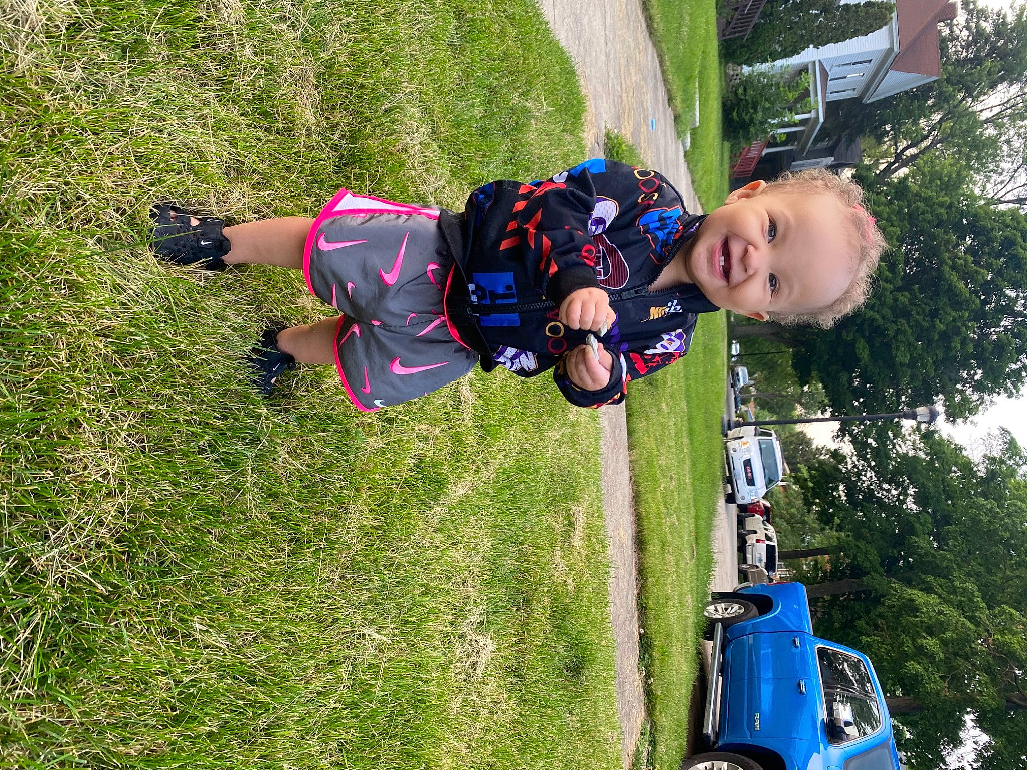 Bella is registered to the contest to win money with this photo: automotive_lighting, baby, car, child, electric_blue, fun, grass, leisure, motor_vehicle, people_in_nature, person, plant, recreation, rolling, smile, tire, toddler, tree, vehicle, wheel