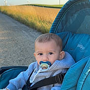 Kayden a rejoint le concours — aidez-le/la à gagner de superbes lots ! baby, child, stroller, pacifier, hoodie, outdoor, path, grass, wind_turbine, sky, daylight, nature, portrait, infant, seatbelt, toy, blue, teal, calm, cute