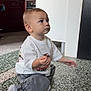 Kayden a rejoint le concours — aidez-le/la à gagner de superbes lots ! toddler, child, sitting, floor, indoor, white_shirt, gray_pants, curious, young_child, person, tile_floor, casual_clothing, short_hair, small_hands, candid, home_interior, kitchen, modern, expression, light
