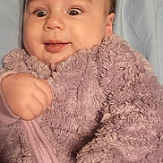 Madeline is registered to the contest to win money with this photo: baby, infant, onesie, purple, fluffy, clothing, hand, face, expression, surprise, bed, blanket, soft, cute, young, child, skin, portrait, sleepwear, indoors