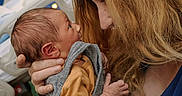 Finnick is registered to the contest to win money with this photo: affection, baby, bed, child, closeup, clothing, emotion, face, hand, holding, hospital, hospital_room, love, newborn, parent, person, portrait, skin, tenderness, woman