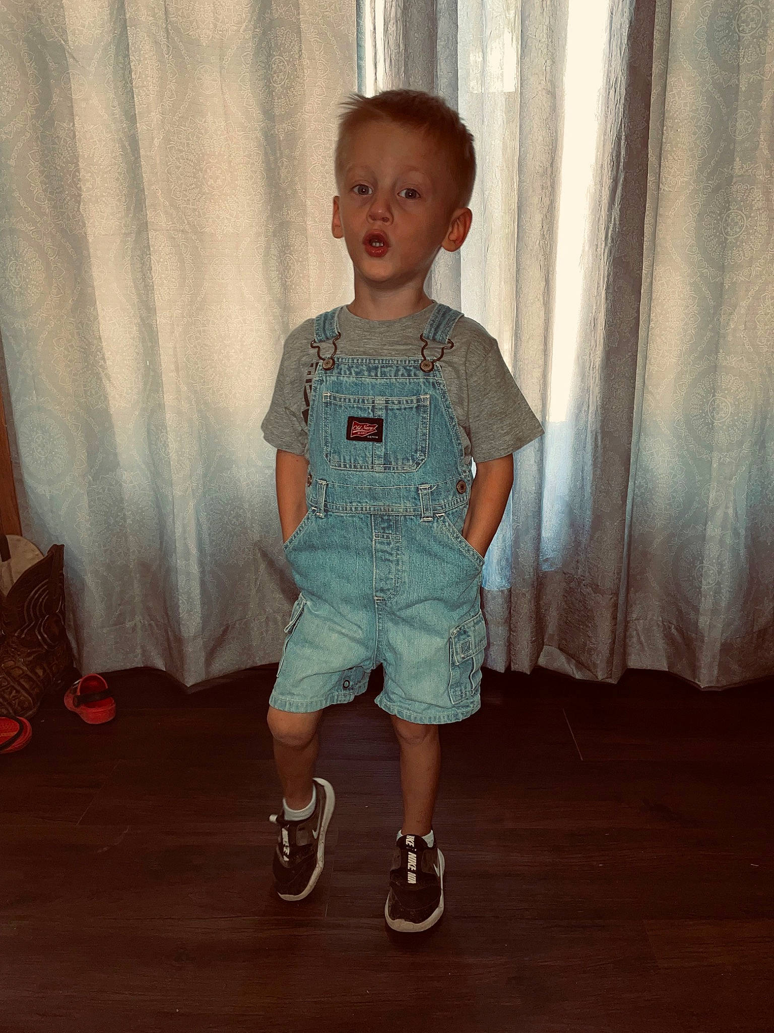 Linton is registered to the contest to win money with this photo: arm, baby_toddler_clothing, curtain, denim, eye, face, floor, flooring, happy, head, human_body, jeans, leg, neck, person, shorts, sleeve, standing, trunk, waist