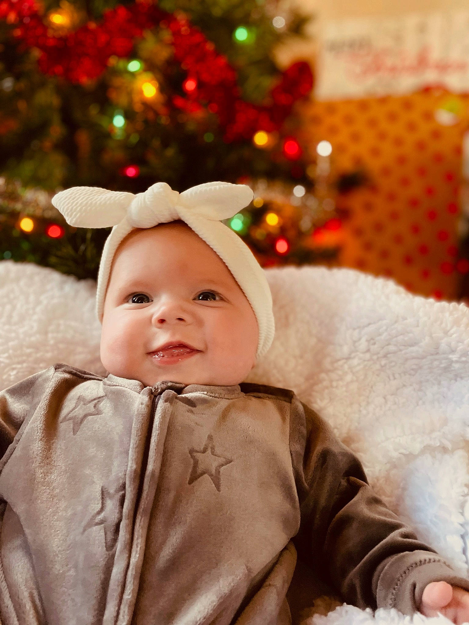 Lillian joined the competition — help win amazing prizes! baby, christmas, christmas_decoration, christmas_ornament, christmas_tree, event, eye, facial_expression, fun, happy, head, holiday, holiday_ornament, human_body, light, lighting, ornament, person, smile, toddler