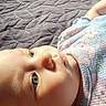 baby, infant, child, face, eyes, blue_eyes, lying_down, bed, blanket, quilt, pajamas, clothing, portrait, indoors, close_up, looking_at_camera, skin, head, photography, patterned_fabric
