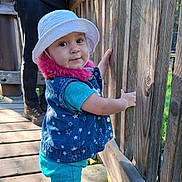 Meredith joined the competition — help win amazing prizes! toddler, child, hat, blue_clothing, vest, wooden_deck, wooden_railing, outdoor, daylight, person, smiling, standing, curious, casual_wear, nature, portrait, footwear, sunlight, hand, background_person