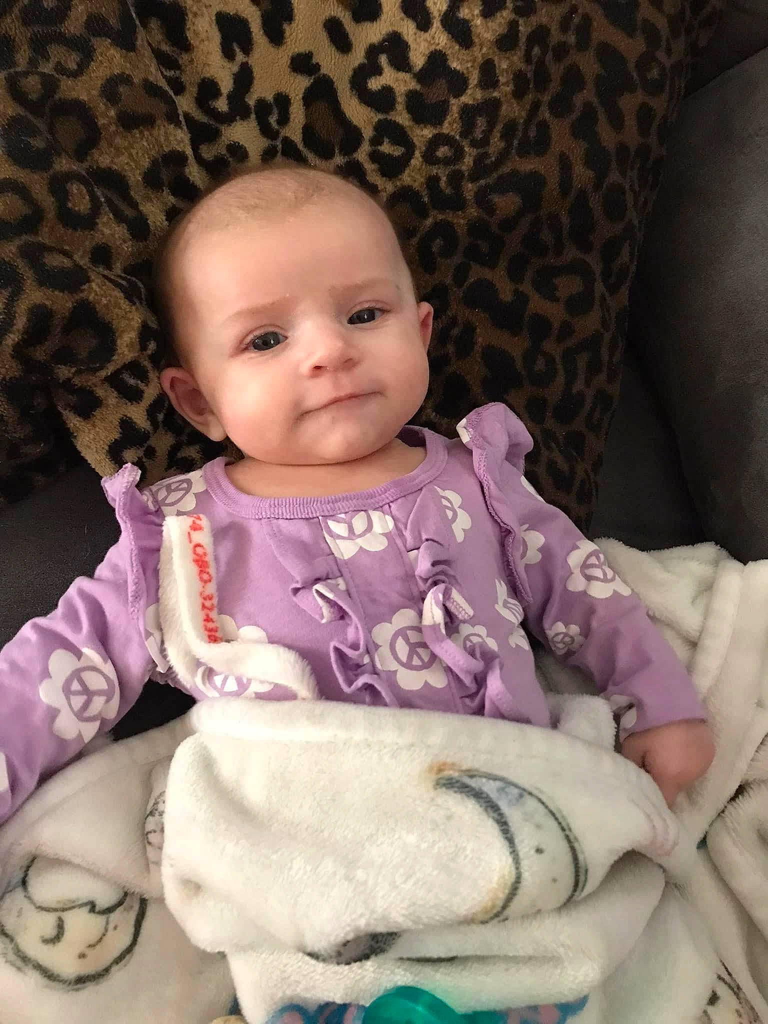 Micaela is registered to the contest to win money with this photo: baby, baby_products, baby_toddler_clothing, bib, cheek, child, comfort, dress, eye, hairstyle, head, iris, linens, lip, person, pink, purple, sitting, skin, sleeve