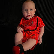 Gabriel is registered to the contest to win money with this photo: baby, child, red_clothing, sitting, couch, indoor, portrait, infant, cute, happy, face, legs, hand, sock, shorts, tshirt, background, expression, person, photography