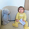 baby, bunny, card, child, couch, cozy, cute, face, furniture, indoor, infant, looking_up, person, plush_toy, portrait, sitting, small_hand, soft_toy, yellow_onesie, young_child