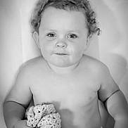 Austin is registered to the contest to win money with this photo: baby, child, curly_hair, blanket, knitted, smile, portrait, black_and_white, cute, innocence, soft_lighting, sitting, young_child, toddler, hand, face, expression, skin, indoors, cozy