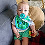 Wyatt is registered to the contest to win money with this photo: baby, bib, blue_eyes, child, couch, cute, green_clothing, home, indoor, infant, mohawk_hairstyle, pacifier, person, pillow, plastic_rings, playful, relaxed, shorts, sitting, toy