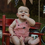 Wyatt joined the competition — help win amazing prizes! american_flag, baby, child, cute, daylight, finger_in_mouth, flag_bunting, grass, happy, outdoor, overalls, playful, portrait, red_chair, sitting, smiling, summer, vintage_wagon, young_child