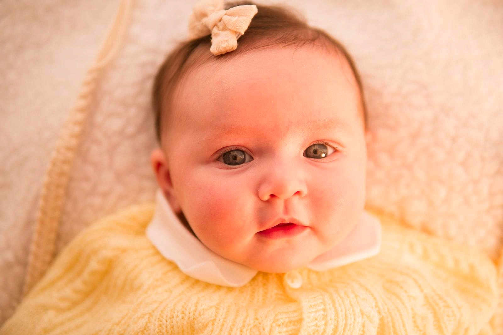 Emy participe au concours pour gagner de l'argent avec cette photo : baby, infant, child, portrait, close_up, eyes, headband, bow, sweater, yellow_clothing, collar, button, blanket, soft_lighting, warm_tone, chubby_cheeks, cute, looking_at_camera, newborn, skin