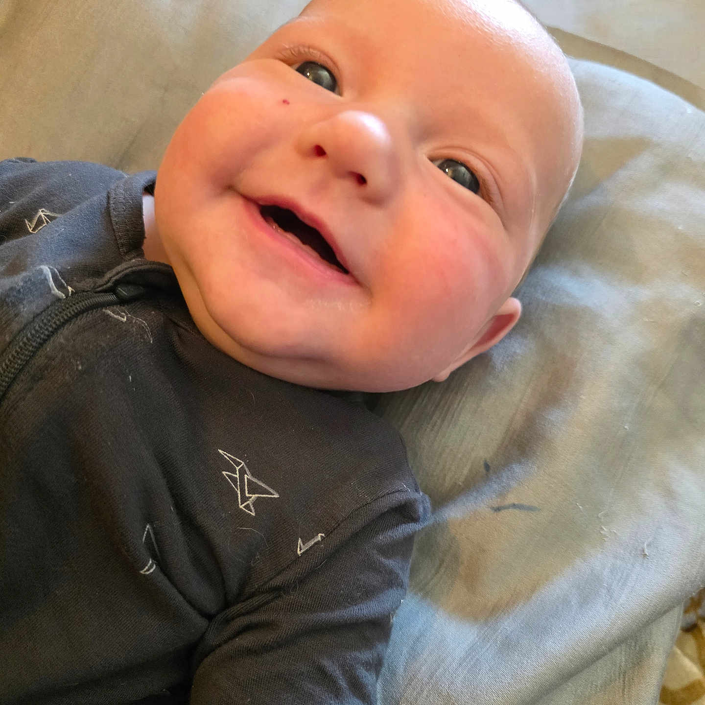 Cohen joined the competition — help win amazing prizes! baby, smile, onesie, infant, face, happy, lying_down, blanket, clothing, child, cute, portrait, skin, head, expression, young, indoors, person, closeup, infancy