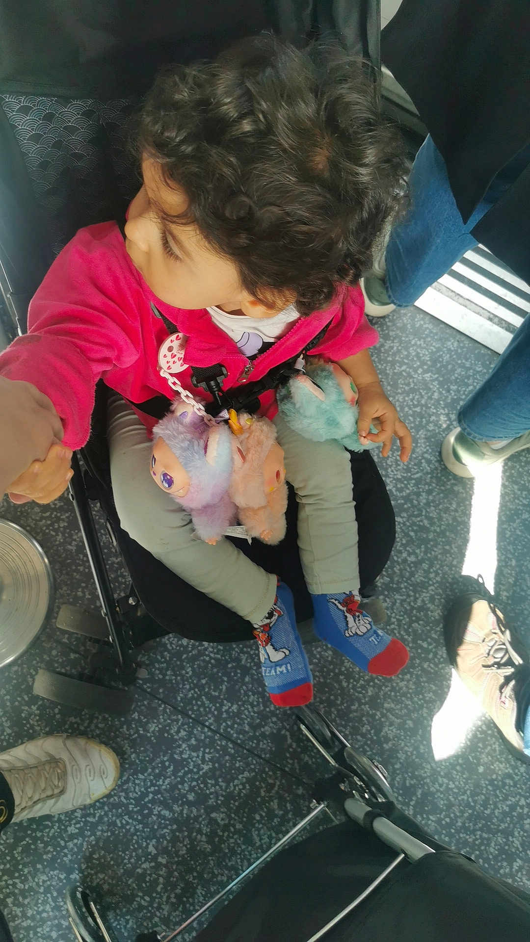 Rabbia a rejoint le concours — aidez-le/la à gagner de superbes lots ! child, toddler, curly_hair, pink_jacket, plush_toys, stroller, socks, cartoon_socks, hand_holding, floor, shoes, jeans, indoor, person, seat, toy, casual_clothing, looking_sideways, young_child, public_transport
