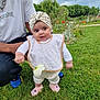 baby, child, flower, grass, garden, bib, headwrap, adult, person, outdoor, nature, greenery, cloudy_sky, footwear, cute, smiling, park, casual_clothing, standing, holding