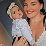 baby, woman, child, smile, headband, bracelet, ring, white_shirt, black_pants, indoor, portrait, family, affection, holding, person, jewelry, home, love, happy, cute