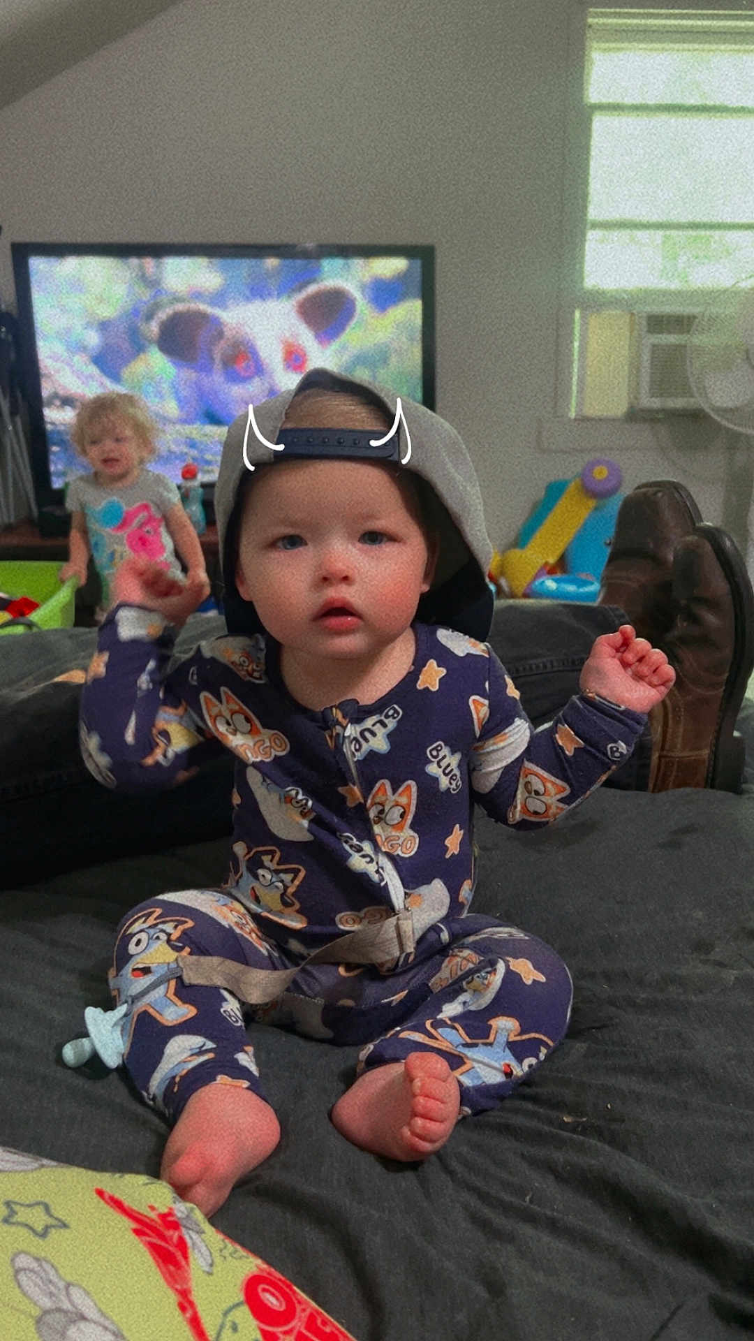 Michael is registered to the contest to win money with this photo: toddler, child, pajamas, hat, cap, bed, indoor, television, animation, cartoon, person, feet, furniture, window, air_conditioner, toy, playroom, expression, face, clothing