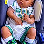 baby, sleeping, car_seat, basketball_outfit, nike_shoes, green_laces, gold_necklace, gold_bracelet, white_socks, curly_hair, child, footwear, infant, cute, portrait, fashion, accessories, relaxing, indoor, toddler