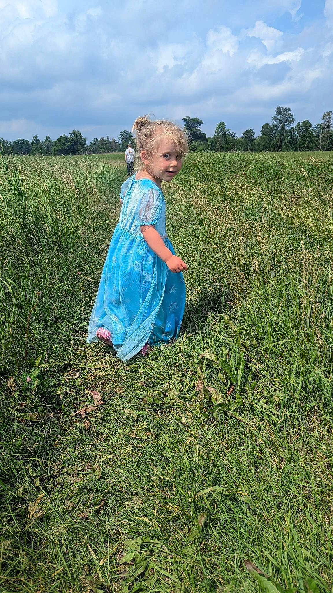 Freya is registered to the contest to win money with this photo: agriculture, baby_toddler_clothing, cloud, electric_blue, field, grass, grass_family, grassland, happy, landscape, meadow, natural_landscape, pasture, people_in_nature, person, plain, plant, prairie, sky, toddler