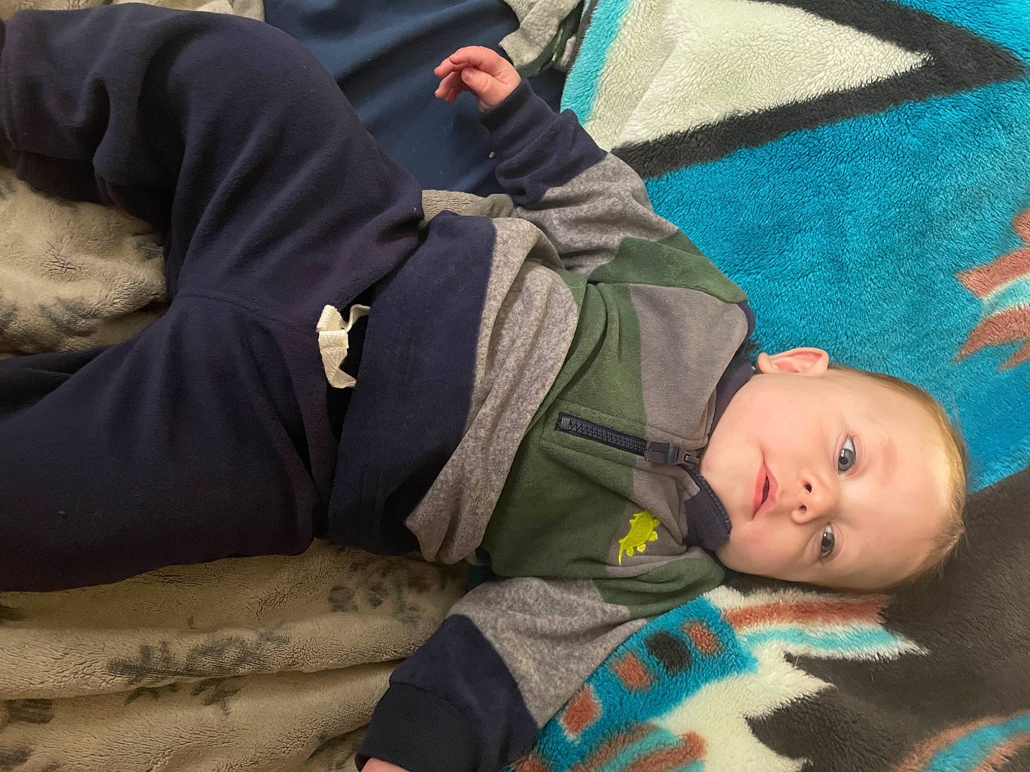 Raiden is registered to the contest to win money with this photo: baby, baby_products, baby_toddler_clothing, camouflage, child, comfort, grass, headgear, linens, military_camouflage, nap, pattern, person, personal_protective_equipment, sitting, sleep, toddler, tree, wood