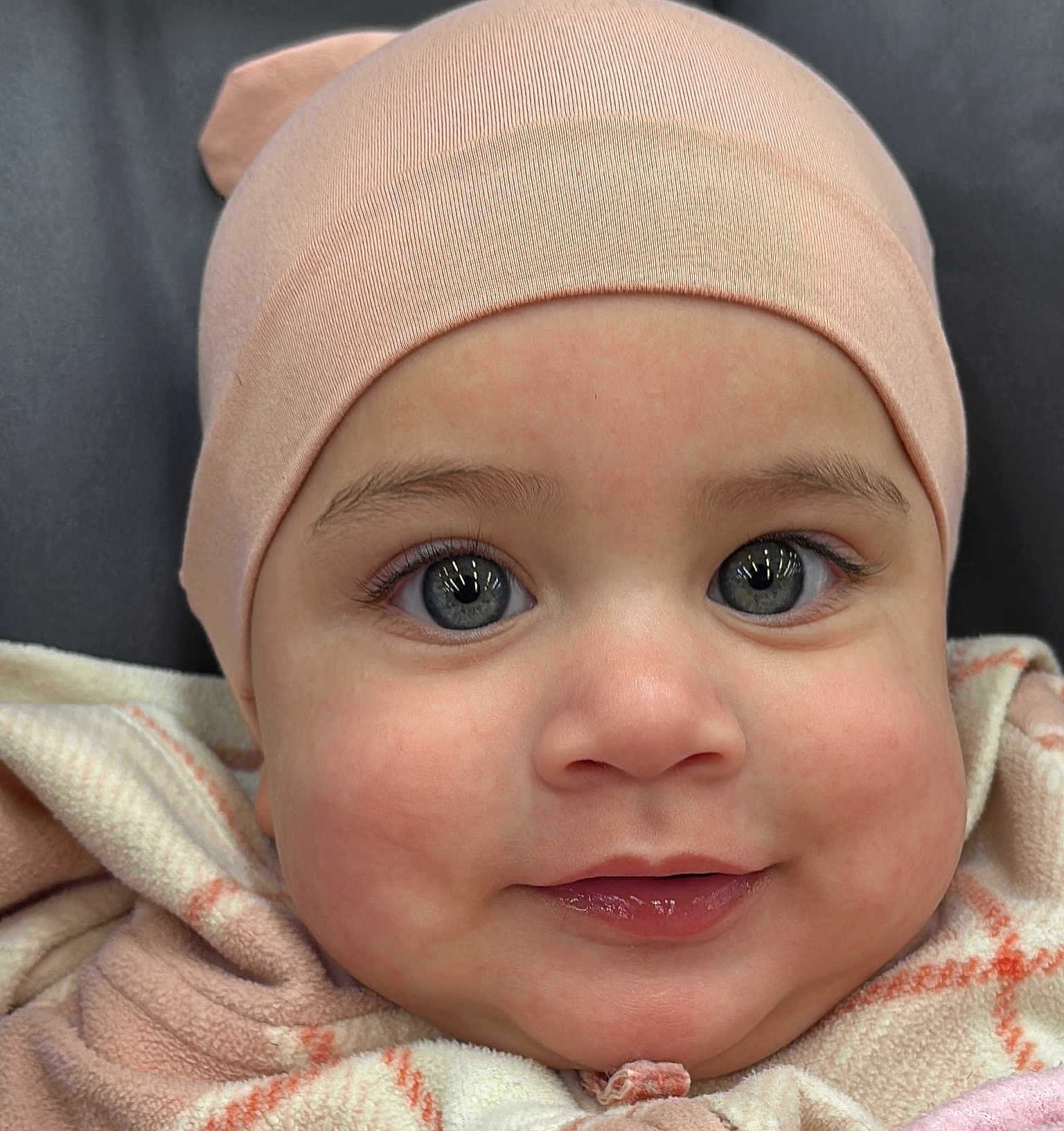 Ashley joined the competition — help win amazing prizes! baby, infant, face, smile, blue_eyes, hat, blanket, closeup, cute, child, apparel, warm_clothing, skin, cheeks, person, portrait, headwear, eyelashes, innocent, happy