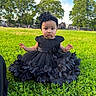 baby, child, grass, greenery, dress, black_dress, headband, flower, outdoor, park, trees, nature, person, portrait, young_child, sitting, sunlight, daylight, face, expression