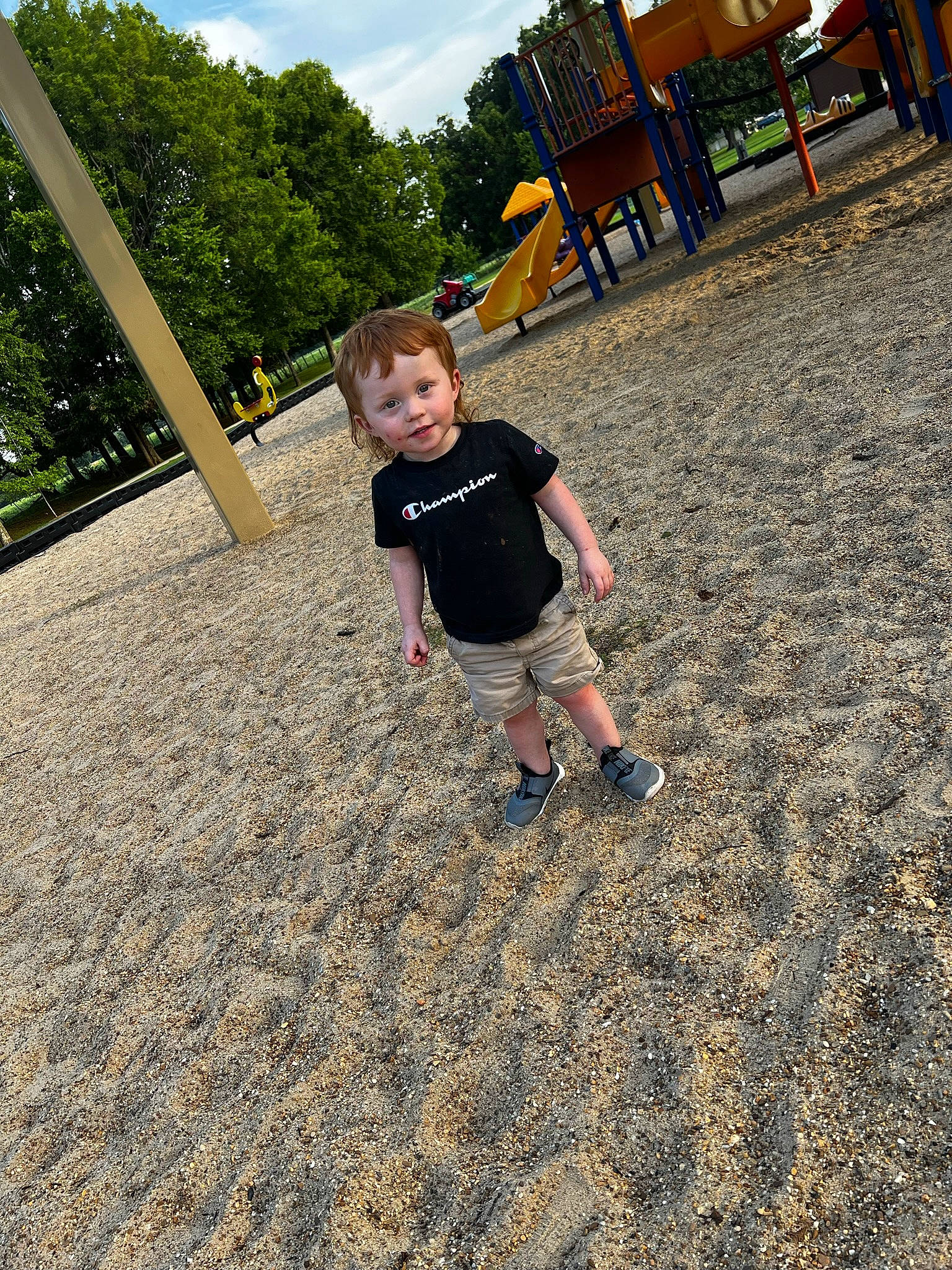 Brody is registered to the contest to win money with this photo: asphalt, child, city, cloud, fun, grass, happy, landscape, leisure, outdoor_play_equipment, people_in_nature, person, plant, playground, public_space, recreation, sky, soil, t_shirt, toddler