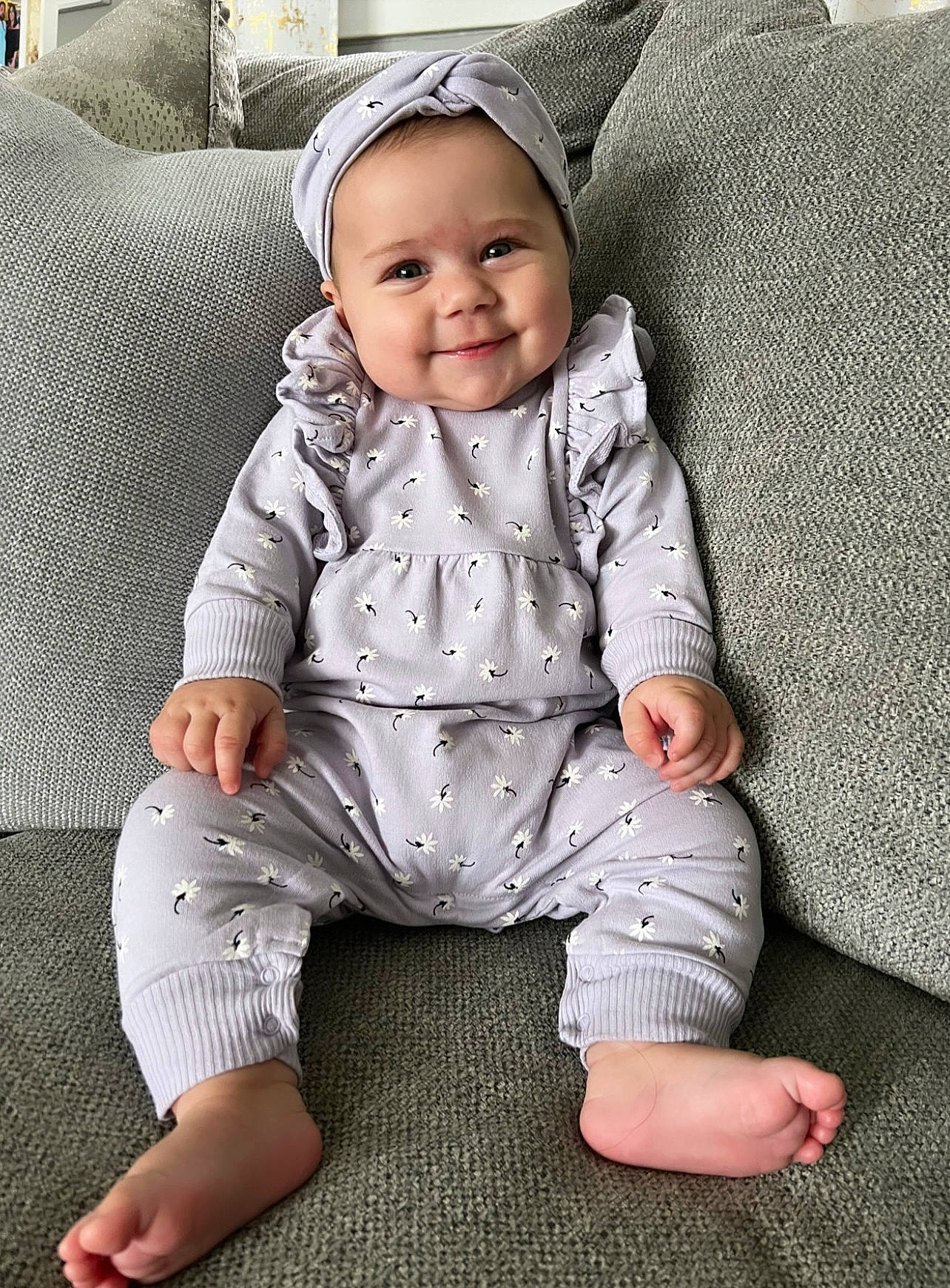 Valentina is registered to the contest to win money with this photo: baby, baby_toddler_clothing, barefoot, child, collar, comfort, couch, dress_shirt, eye, face, flooring, foot, grey, happy, headwear, joy, pattern, person, sitting, skin