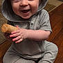 baby, child, hoodie, gray_clothing, wooden_floor, toy, smiling, happy, sitting, indoor, cute, infant, face, blue_eyes, hands, feet, wooden_toy, hood, candid, portrait