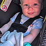 Hunter is registered to the contest to win money with this photo: baby, car_seat, child, smiling, plush_toy, pacifier, seatbelt, infant, soft_toy, blue_shirt, closeup, cute, happy, indoors, person, toddler, face, safety, comfort, young_child