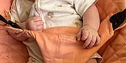 Freya is registered to the contest to win money with this photo: baby, smiling, infant, onesie, animal_print, seat, peach_color, happy, cute, child, skin, hand, legs, indoor, comfort, fabric, clothing, young, portrait, person