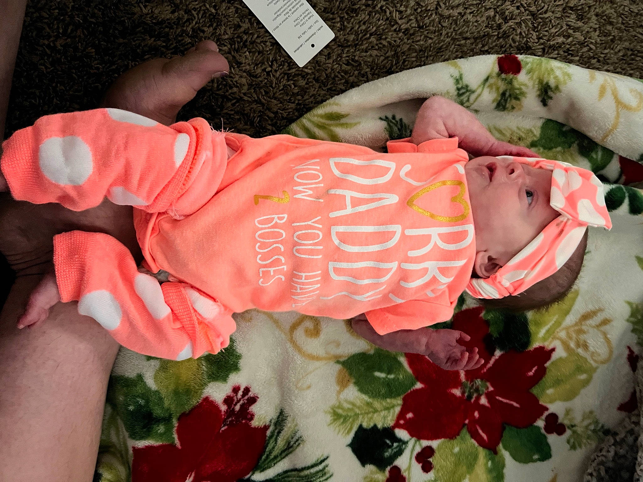 Aurora June is registered to the contest to win money with this photo: baby_products, baby_toddler_clothing, carmine, child, cut_flowers, dress, floral_design, flower_arranging, font, headwear, human_leg, linens, orange, pattern, peach, person, petal, pink, plant, rose