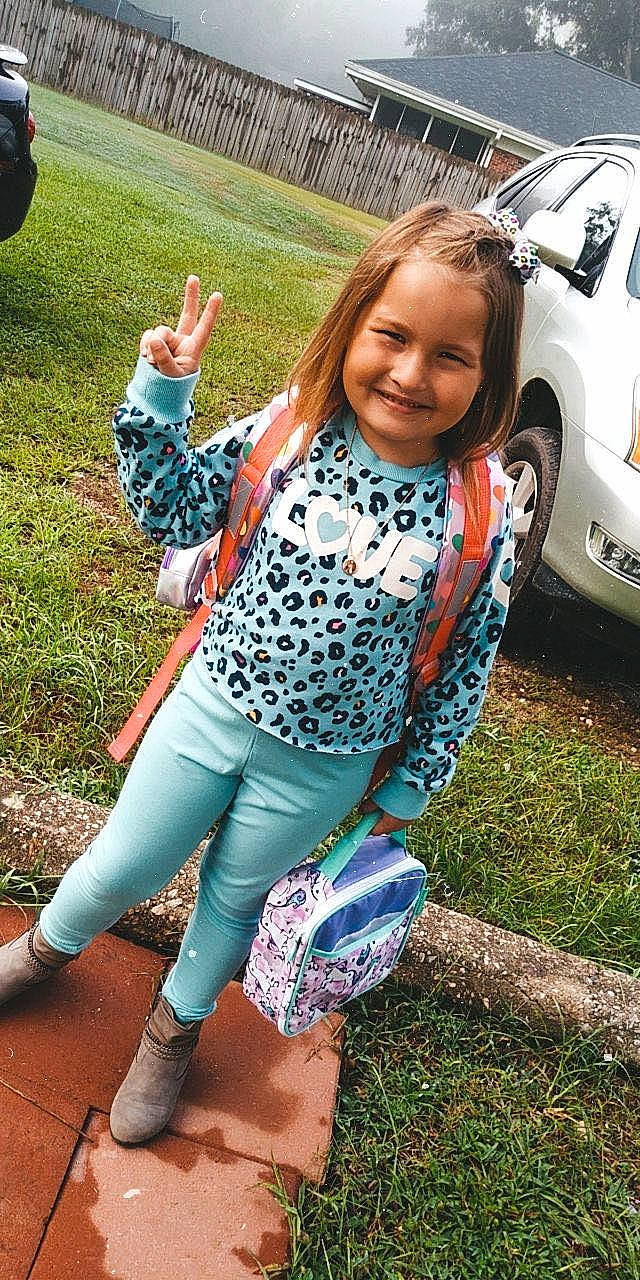 Ansley is registered to the contest to win money with this photo: car, electric_blue, eyewear, face, grass, happy, human_leg, joy, leg, leisure, pattern, person, plant, shoe, sleeve, smile, sportswear, thigh, tire, trunk