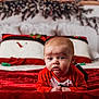 baby, infant, red_clothing, blanket, bed, pillow, snowman, holiday, christmas, decor, face, person, indoors, cozy, cute, expression, plush, festive, child, toddler
