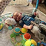 Ethan is registered to the contest to win money with this photo: baby, infant, playpen, toys, plush_toy, drum_toys, carpet, clothing, smile, child, floor, colorful, indoor, person, baby_play_area, soft_toys, happy, blanket, crawling_mat, toy_ball