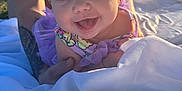 Violet is registered to the contest to win money with this photo: baby, child, smiling, headband, purple_clothing, tattoo, blanket, outdoor, sunlight, happy, person, portrait, infant, cute, closeup, grass, nature, daylight, playful, support