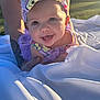 baby, child, smiling, headband, purple_clothing, tattoo, blanket, outdoor, sunlight, happy, person, portrait, infant, cute, closeup, grass, nature, daylight, playful, support