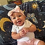 baby, child, smiling, pink_headband, bow, white_shirt, pink_shorts, blanket, moon, stars, butterfly, indoor, happy, sitting, cute, portrait, face, skin, hand, infant