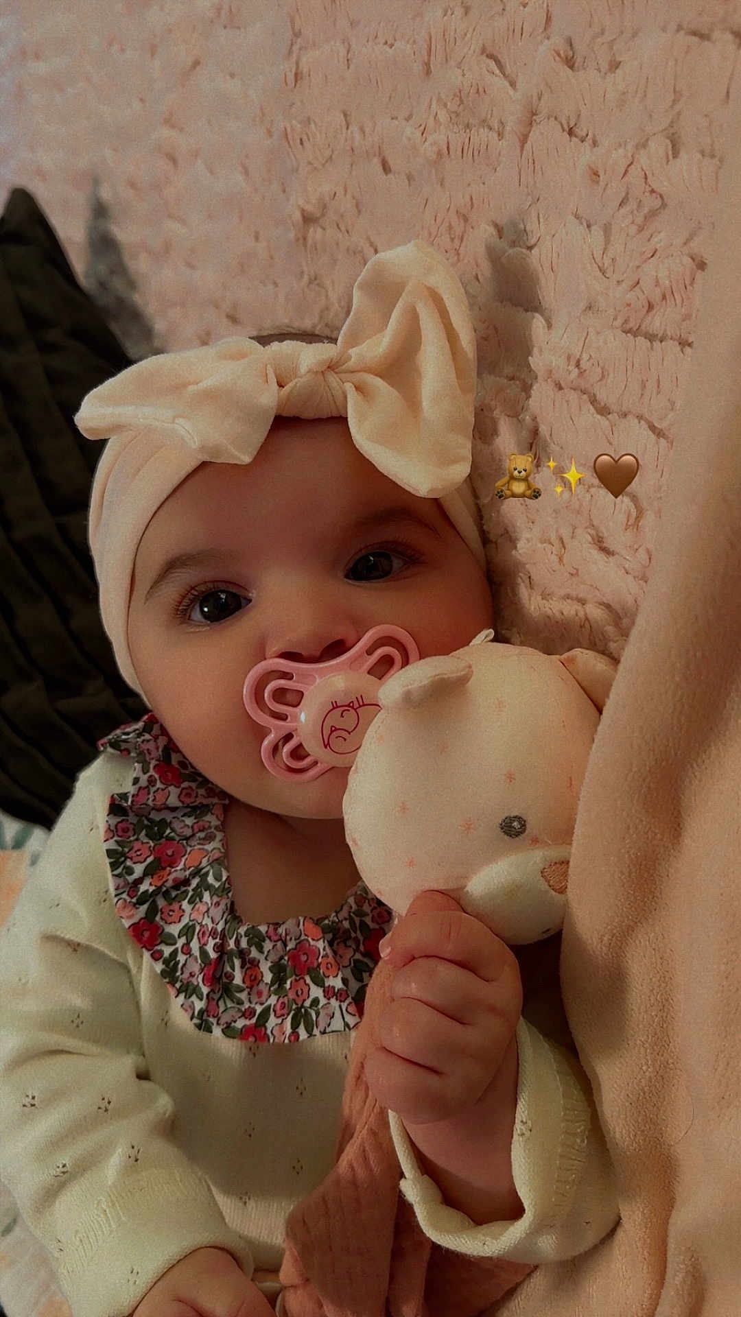 Amalia participe au concours pour gagner de l'argent avec cette photo : baby, blanket, bow, closeup, cozy, emoji_overlay, eyes, floral_collar, hand, headband, indoors, infant, long_eyelashes, onesie, pacifier, pink_tones, plush_toy, portrait, soft_texture, stuffed_animal