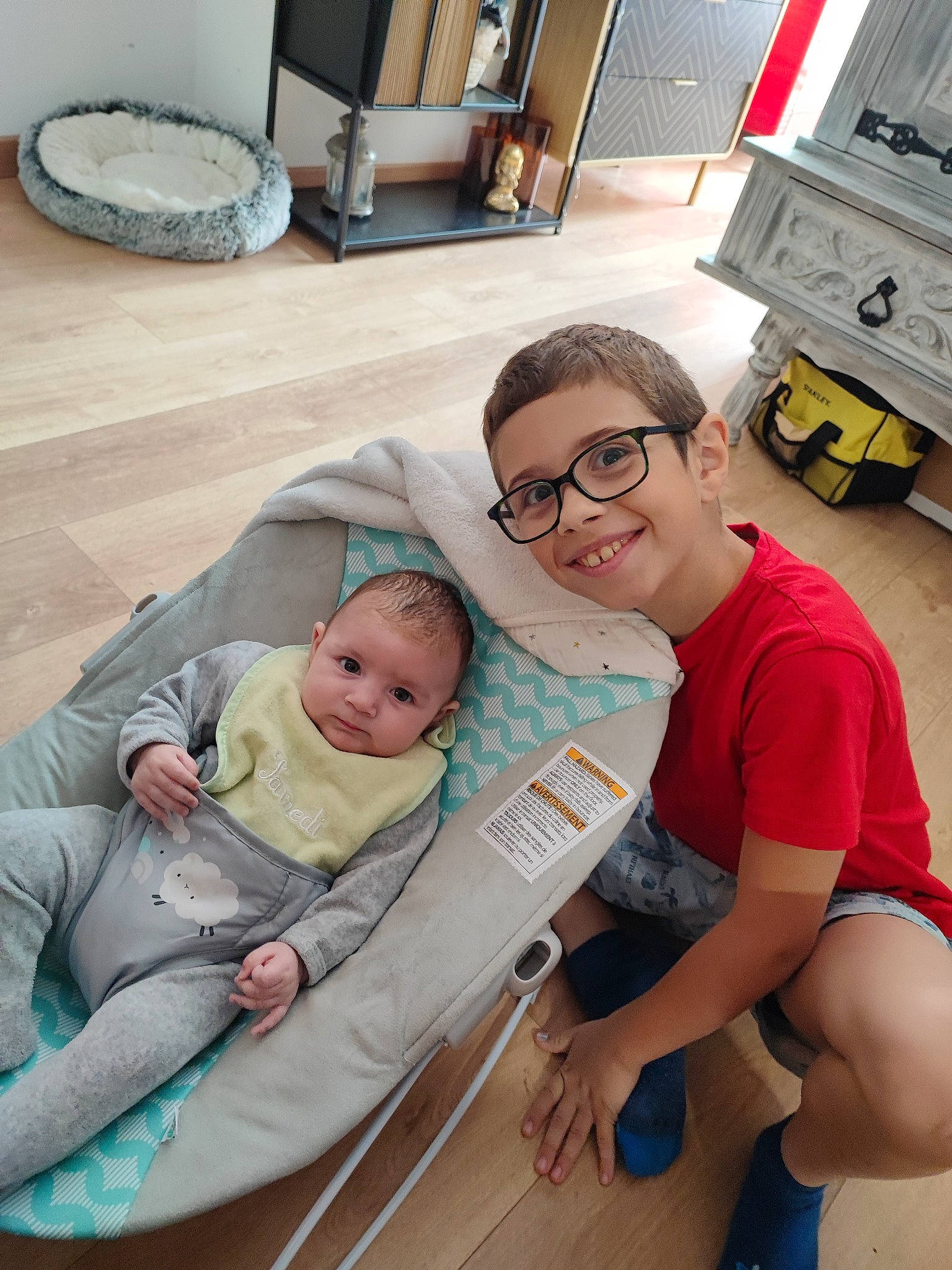 Eloïse participe au concours pour gagner de l'argent avec cette photo : baby, baby_carriage, child, comfort, eyewear, flooring, fun, glasses, happy, joy, lap, leisure, person, product, room, shorts, sitting, skin, smile, thigh